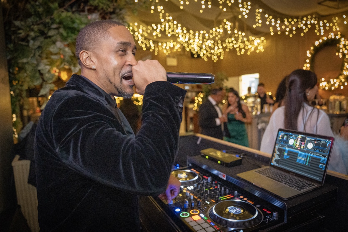 DJ Takeova performing behind a polished professional DJ setup at an event