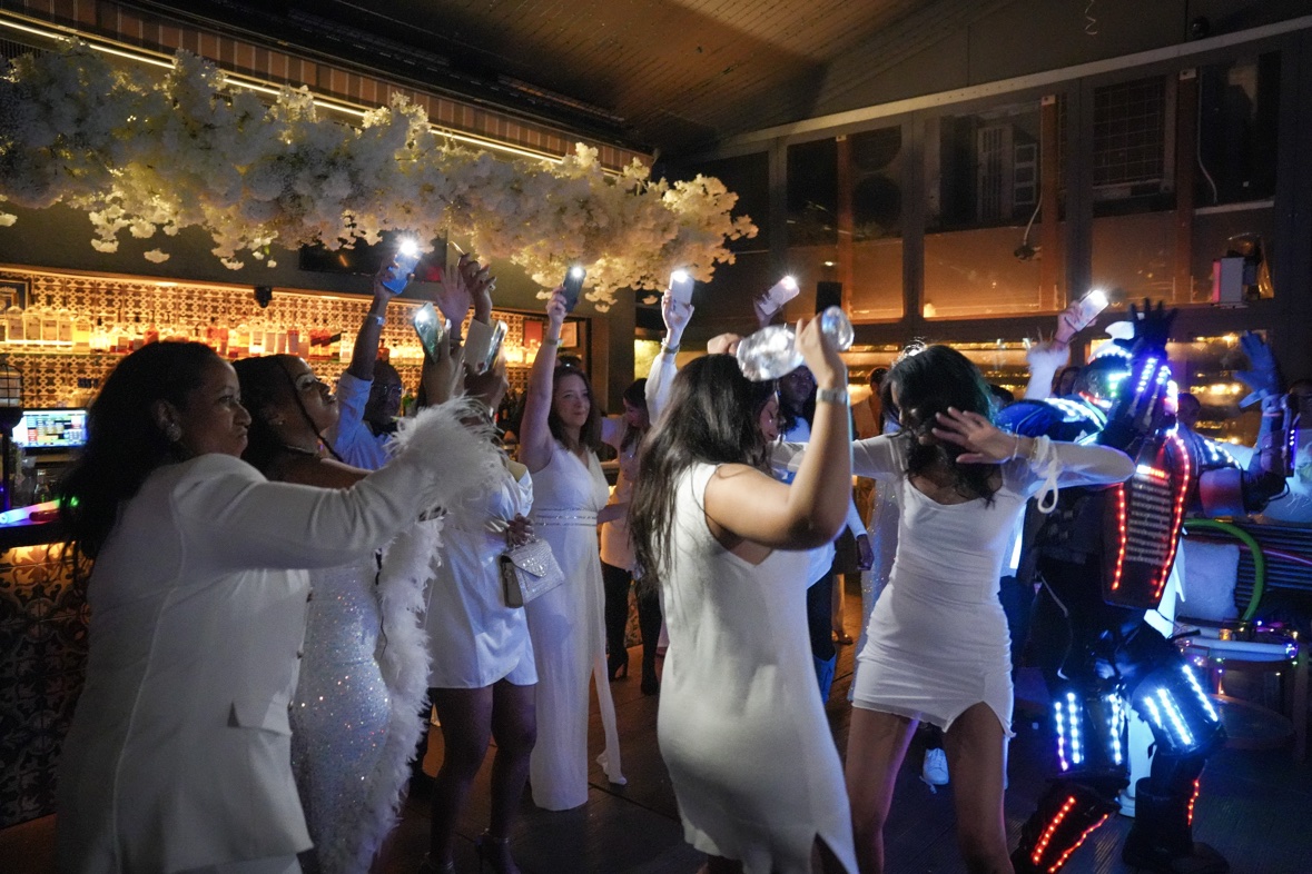 Guests dancing at an all-white party in a lounge