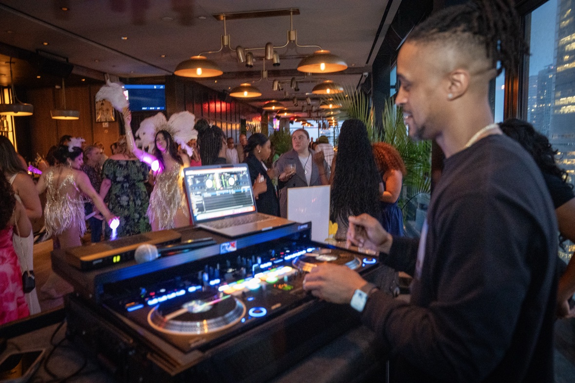DJ Takeova mixing beside a lively lounge crowd