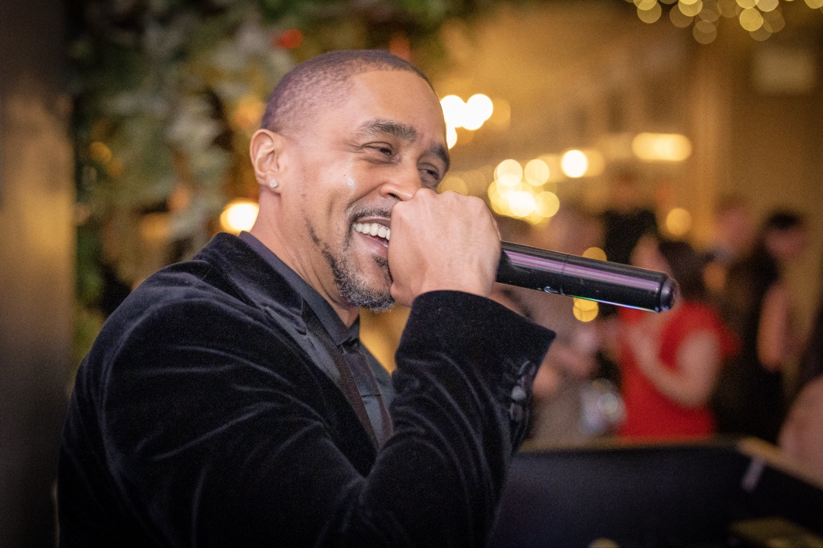 DJ Takeova smiling into the microphone while hosting an event