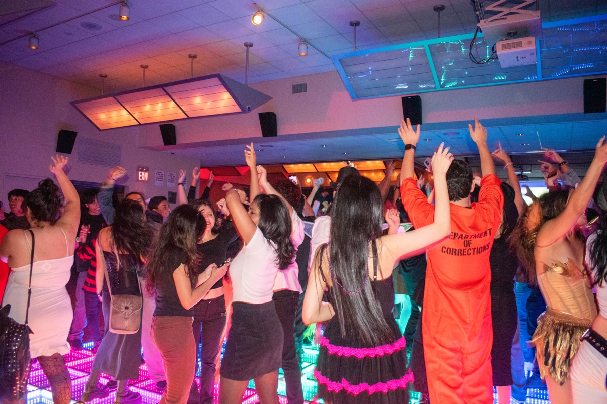 College students dancing with their hands up on a glowing LED dance floor